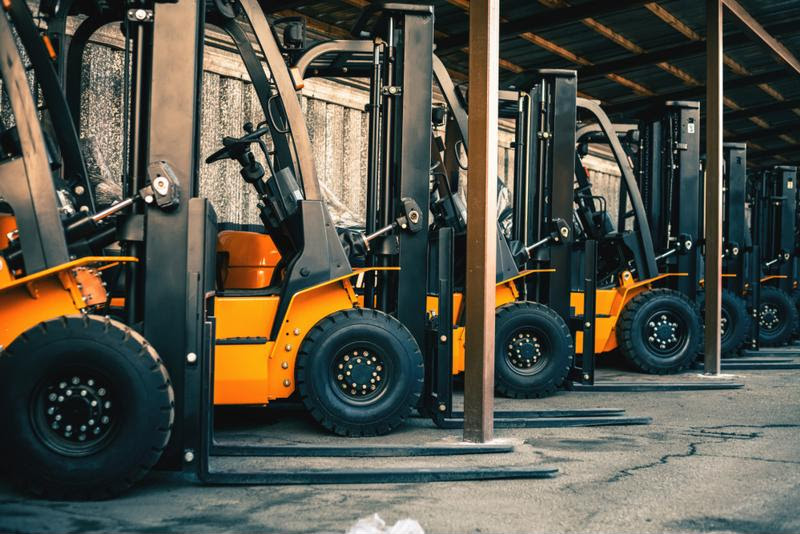A fleet of parked forklifts.
