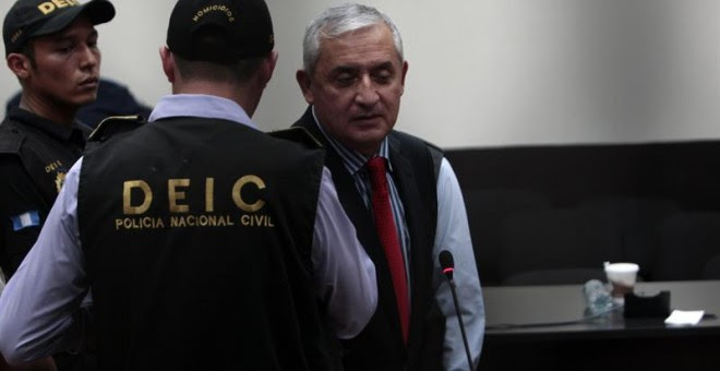 Otto Pérez Molina, custodiado por un policía, es trasladado a la cárcel del cuartel de Matamoros. - EFE