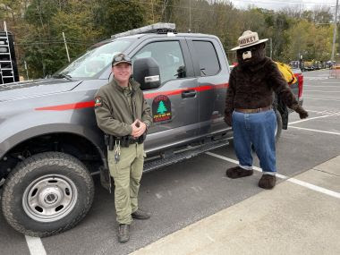Ranger Laymon and Smokey Bear posing for a photo in front of a Forest Ranger truck