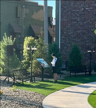 a woman standing next to a sign in a park