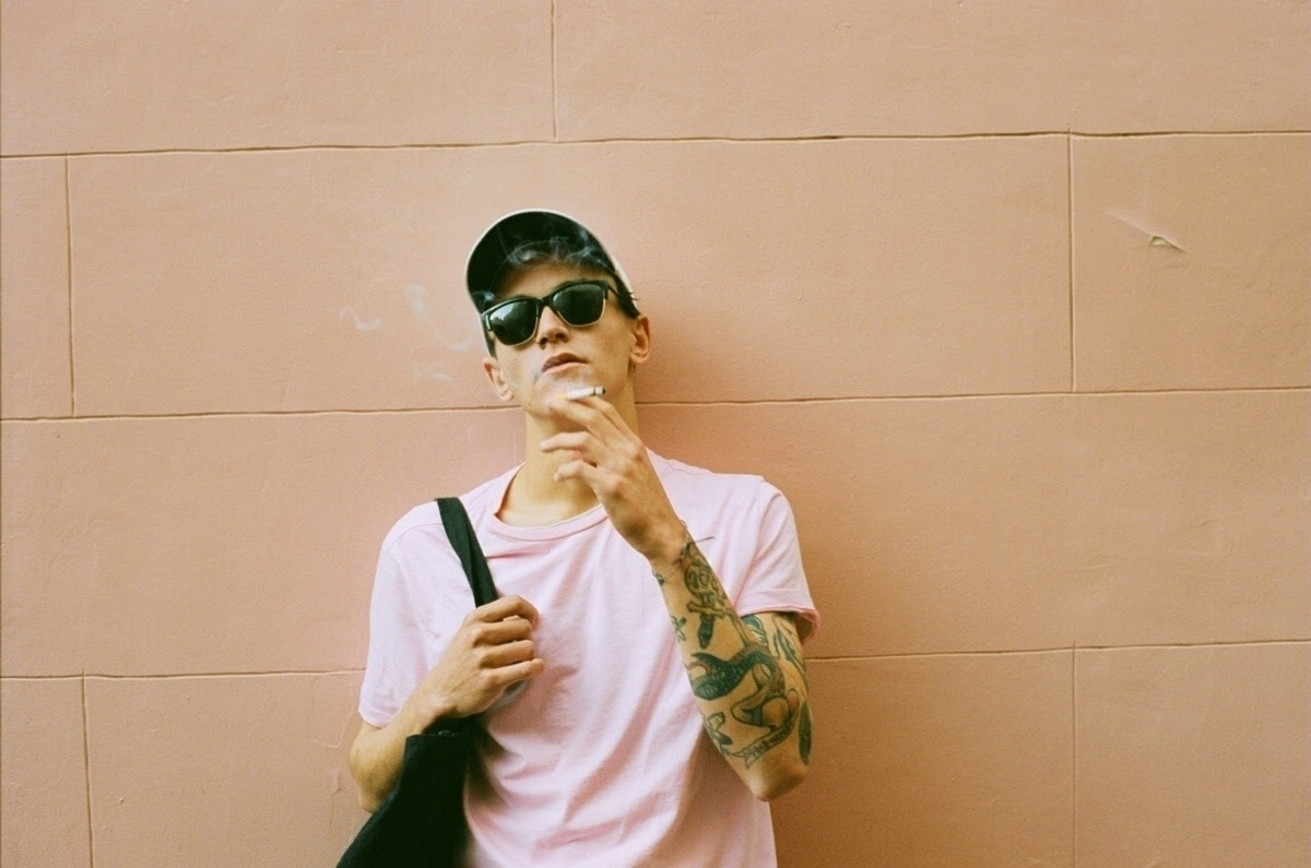 man in pink shirt smoking a cigarette