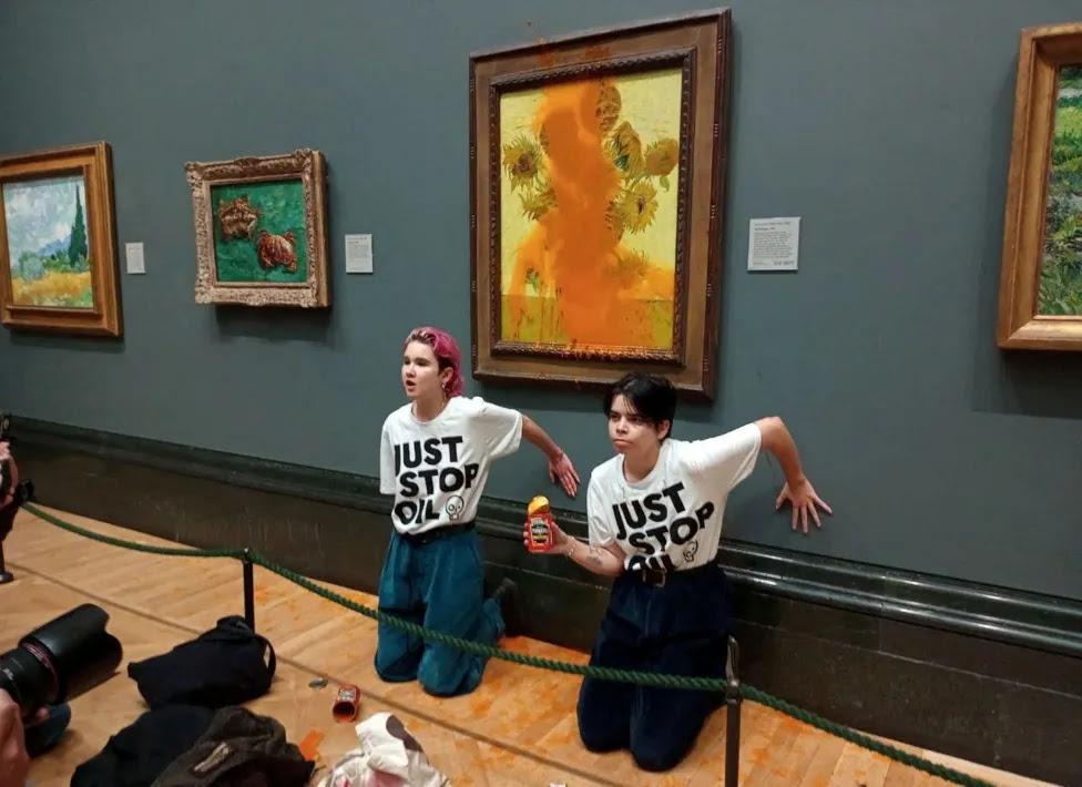 Activists of "Just Stop Oil" glue their hands to the wall after throwing soup at a van Gogh's painting "Sunflowers" at the National Gallery