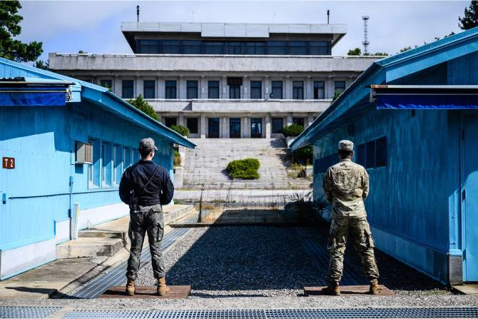 UNC soldiers and a South Korean soldier stand guard before North Korea's Panmon Hall and the military demarcation line separating North and South Korea