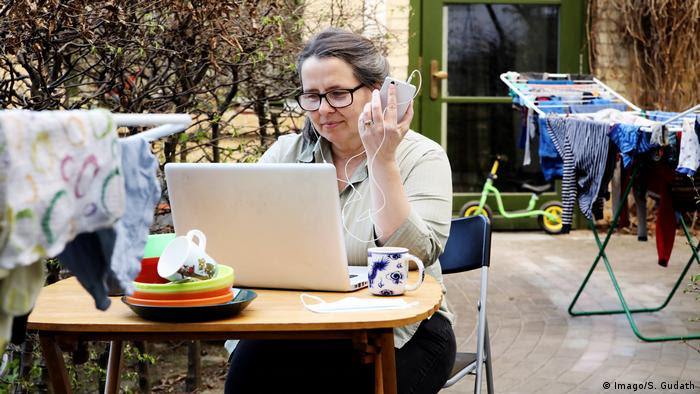 Mulher trabalha com laptop e celular em ambiente doméstico