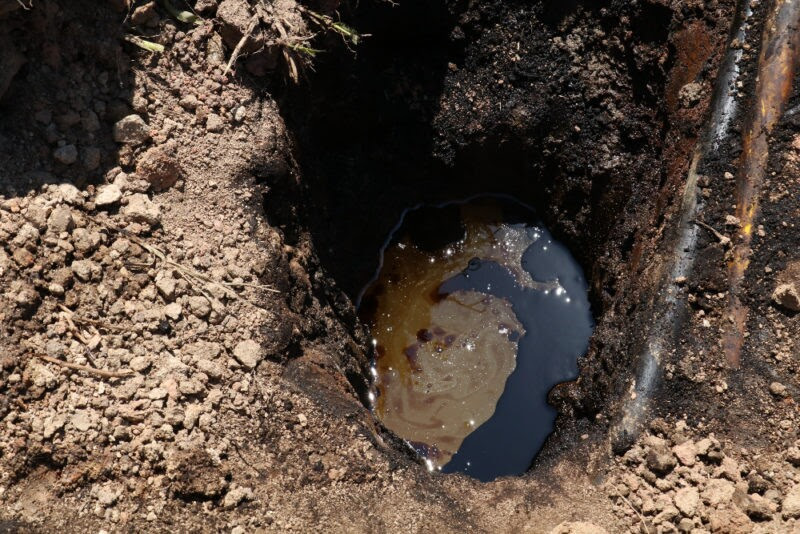 Buraco na terra mostra poça de petróleo