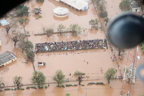 People crowd together on an exposed building in the centre of brown floodwater.