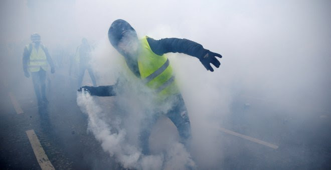 Un hombre, ataviado con un chaleco amarillo, lanza una granada de gas lacrimógeno.- Stephane Mahe/REUTERS