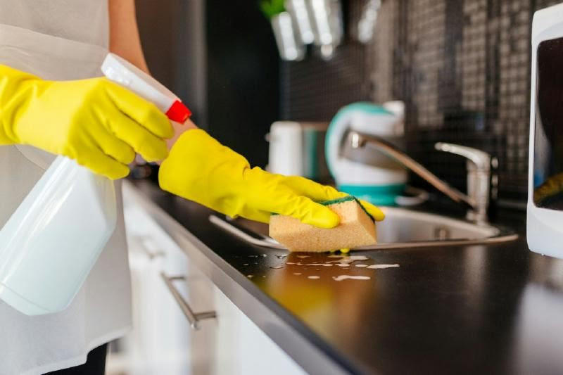 A person cleaning a kitchen counter Description automatically generated