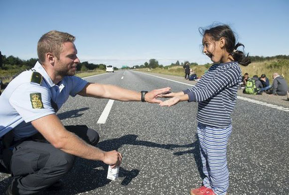 Un policía danés habla con una niña siria migrante. Foto: Reuters