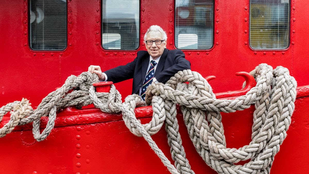 A man in a suit posing on a red boat