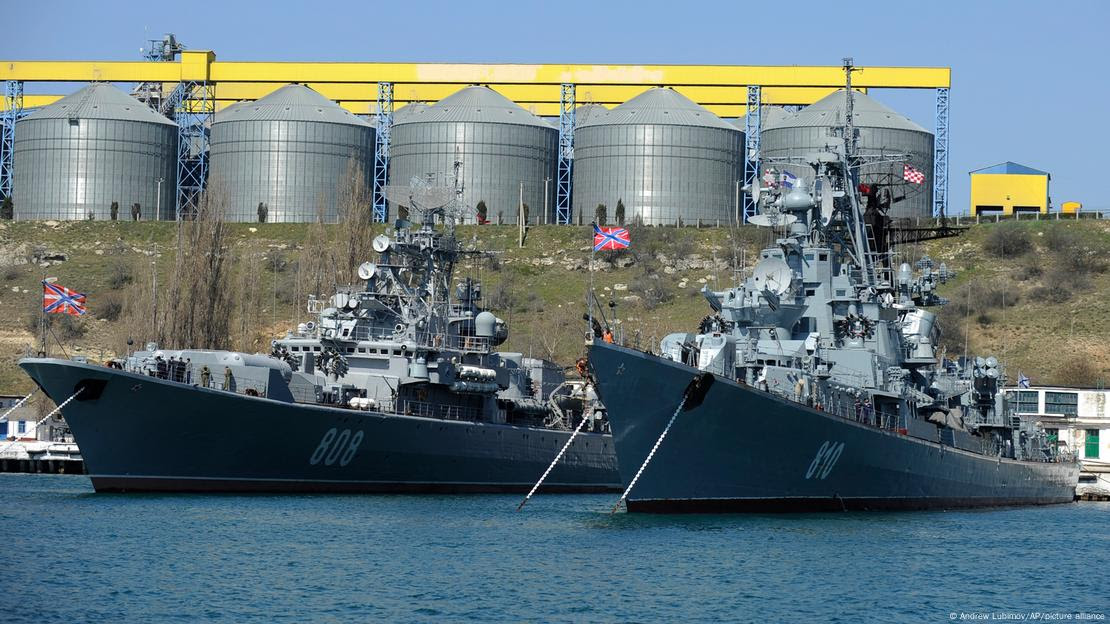 Dois navios de guerra com silos ao fundo