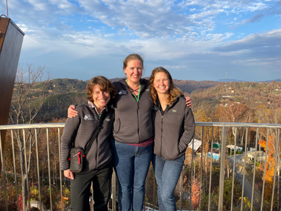 Three women standing on a mountaintop deck.