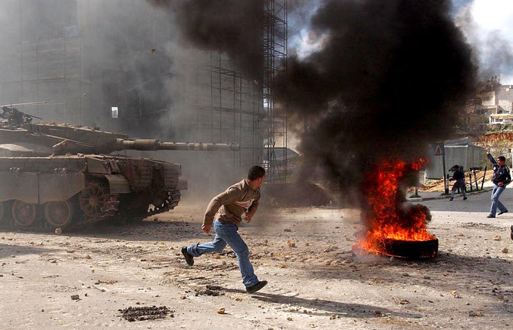 A Palestinian boy runs past Israeli Border Police officers