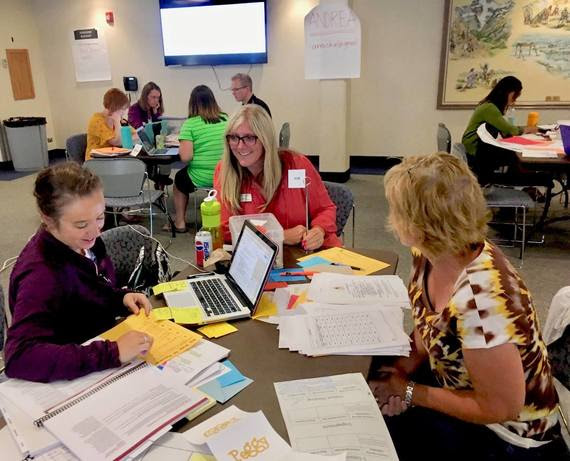 A WDE employee sits with two teachers at a table developing agriculture focused curricula for Wyoming's science standards.