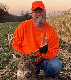 deer hunter with deer he harvested this year holding antlers near corn field and grass