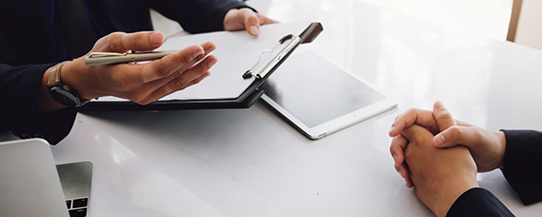 HR representative holding a clipboard while interviewing an employee and asking questions.