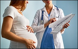 The figure shows a pregnant female looking at medical paperwork with her health care provider.