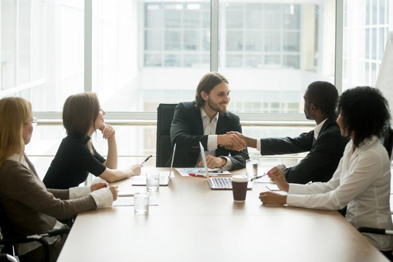 Employees shake hands in a boardroom.