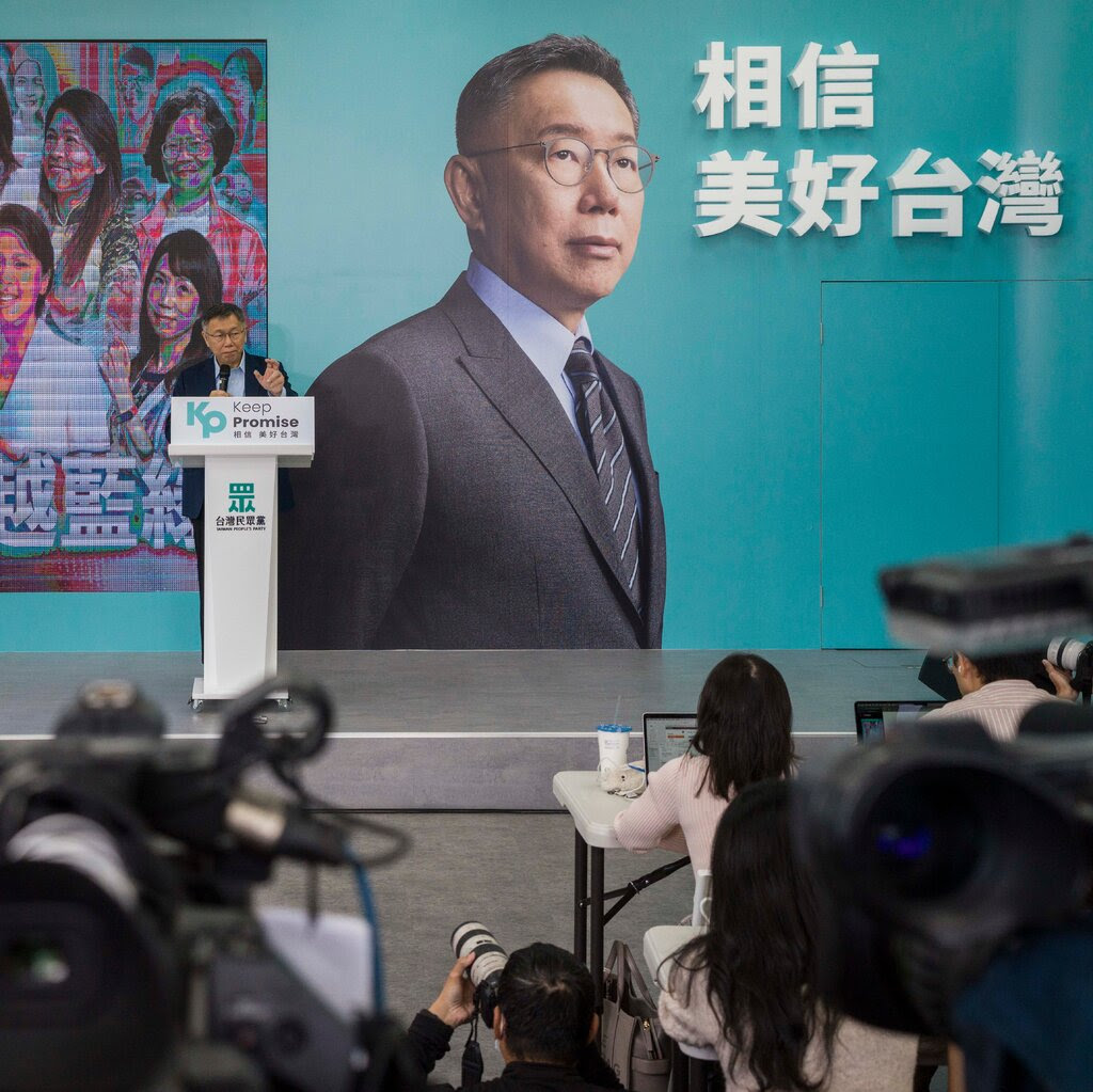 Ko Wen-je habla en un podio con una gran fotografía suya en la pared detrás de él.