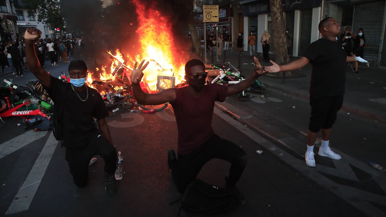 An image of three men standing before a burn pile in the riots