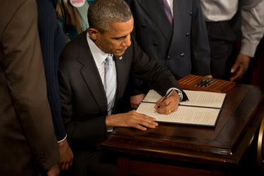 President Obama signing an executive order in February 2014 directing federal contractors to raise their minimum wage for federally funded workers.