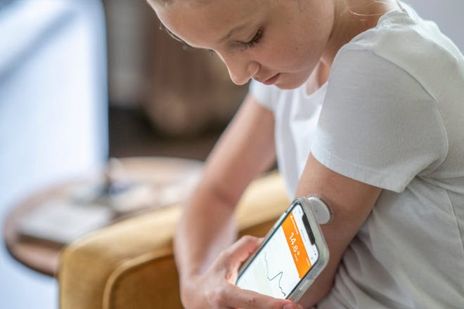 A diabetes patient uses a smartphone to monitor glucose levels.