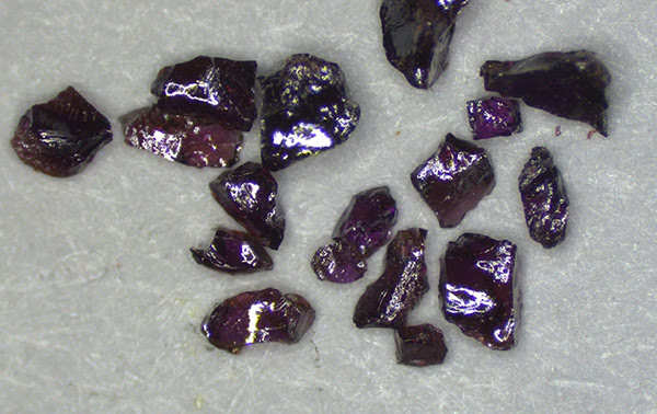 A scatter of sharp-edged, shiny, dark purple crystals.