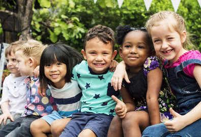 Children smiling together, arm in arm.