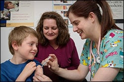 The figure above is a photograph showing a boy being vaccinated by a health care professional, as an adult looks on. 