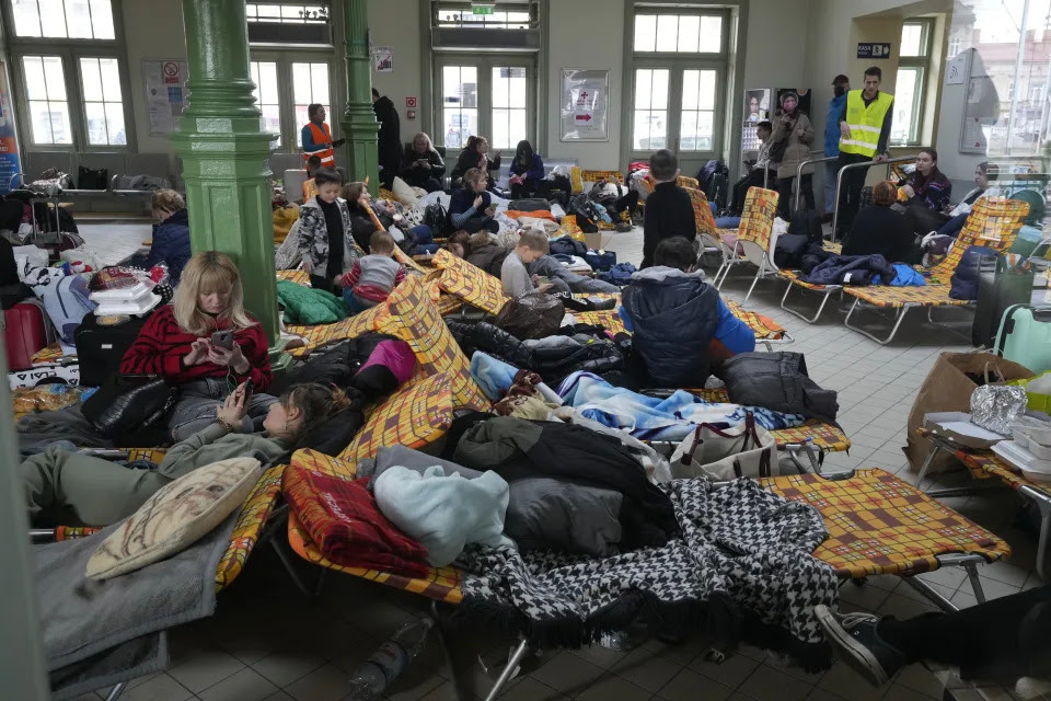 Refugees from Ukraine lie on folding cots set up at a railway station.
