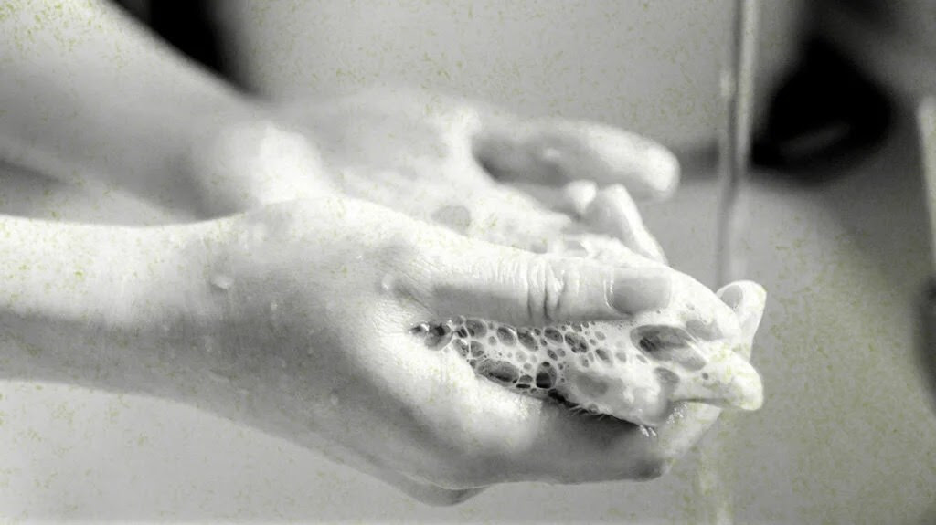 A person washing their hands and nails thoroughly with soap and water.