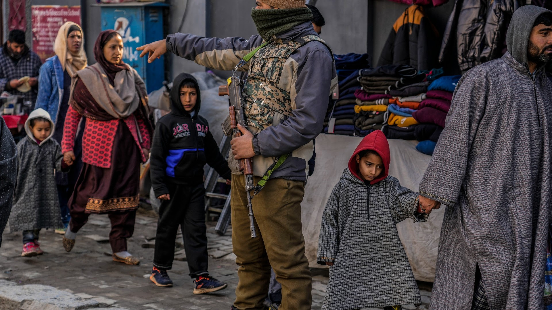 A Kashmiri family walks as an Indian policeman calls a Kashmiri pedestrian for a surprise check as part of enhanced security measures ahead of Republic Day in Srinagar, Indian controlled Kashmir, Monday, Jan. 23, 2023.