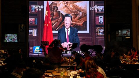 Njerëzit hanë darkën në një restorant ndërsa një ekran transmeton presidenti kinez Xi Jinping duke mbajtur fjalimin e tij të Vitit të Ri në Pekin më 31 dhjetor 2021.