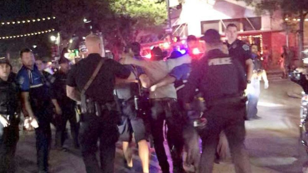 Police officers escort a victim (C) after gunfire erupted at a busy entertainment district in Austin, Texas