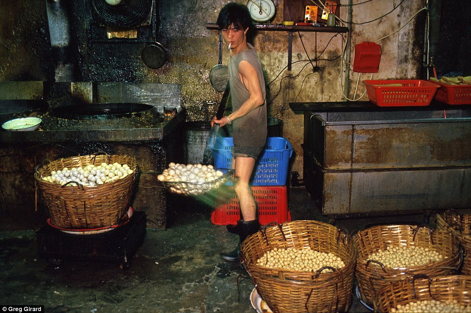 Employee Kwok Tsang Ming ladles a batch of fried fishballs into baskets in a small factory off Kwong Ming Street