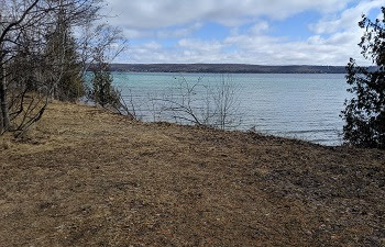 view from the shore of a 2-plus-acre land parcel on Torch Lake with 200 feet of lake frontage, blue sky and clouds 