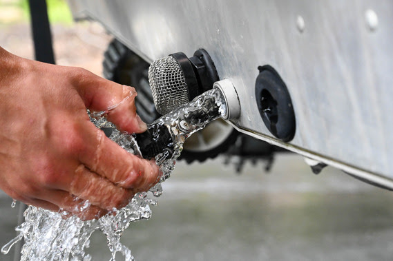 person pulling drain plug from boat