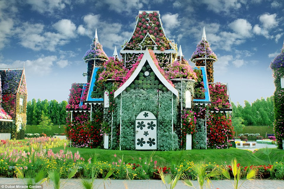 A fantasy flower house at the Miracle Garden, which has plants growing over its turrets, doors, walls and towers
