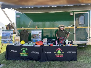 Forest Ranger stands behind an informational table at DEC booth