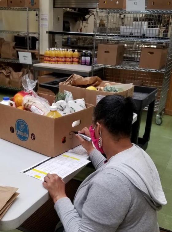 Volunteer writing on box of groceries