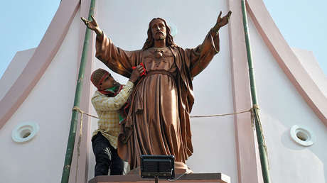 Un trabajador limpia una estatua de Jesucristo antes de las celebraciones de Navidad en las afueras de Agartala, India.