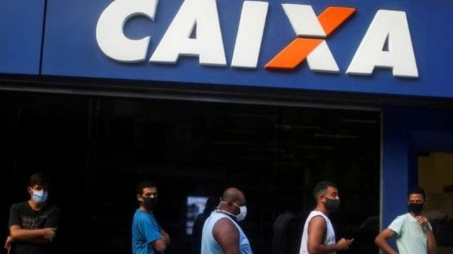 Pessoas de máscara aguardam na fila da Caixa Econômica