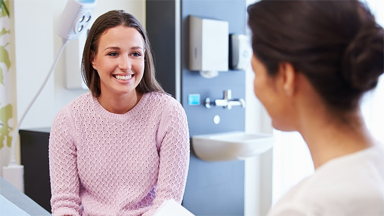 The figure shows a patient talking with a health care provider in an exam room.