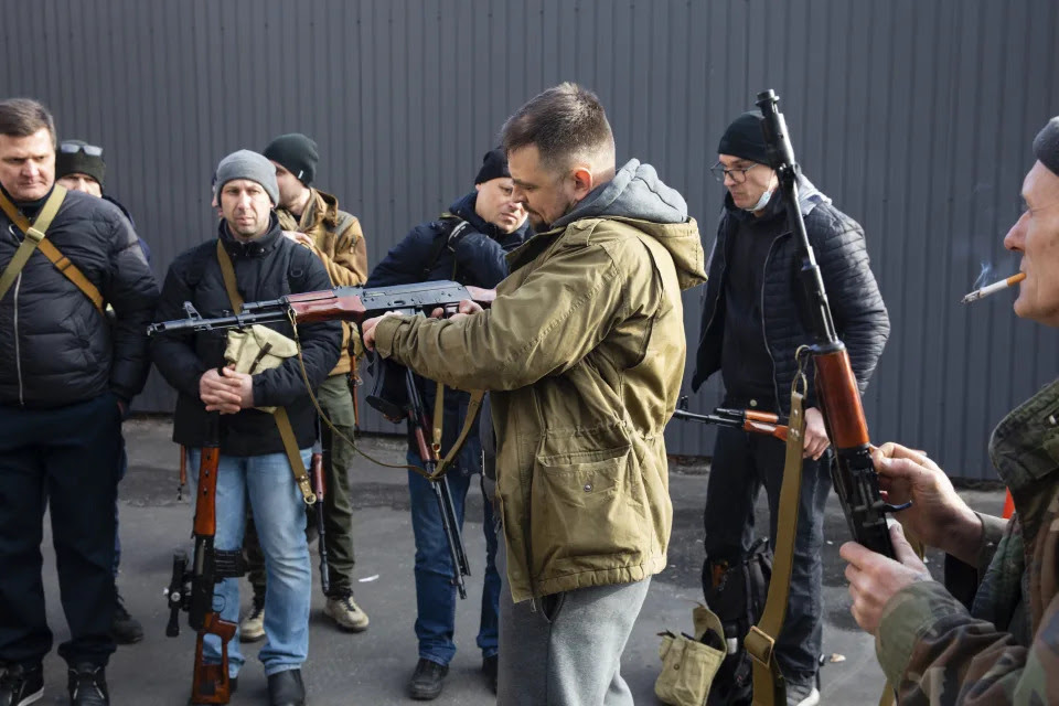 Civilian members of a territorial defense unit check their weapons.