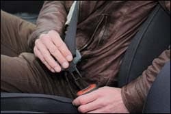 The figure above is a photograph showing a man about to buckle his seat belt.
