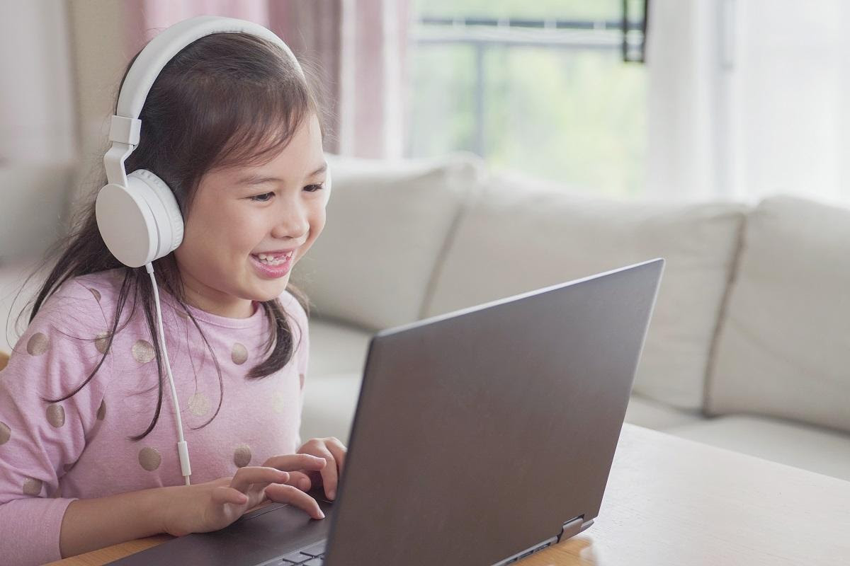child wearing headphones and using laptop at home