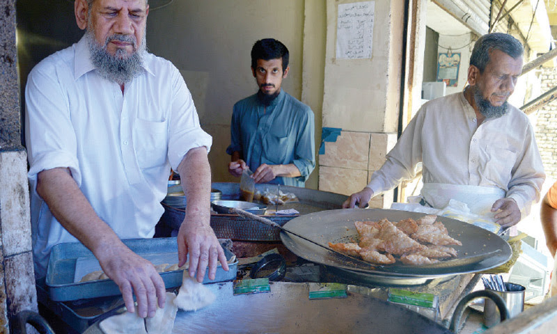 (TOP) Sheikh Lateef, the owner of the shop, is seen frying Samosas while the other picture is of a worker preparing the triangular delight. — Photos by Khurram Amin