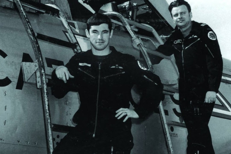 Two pilots stand next to a plane.