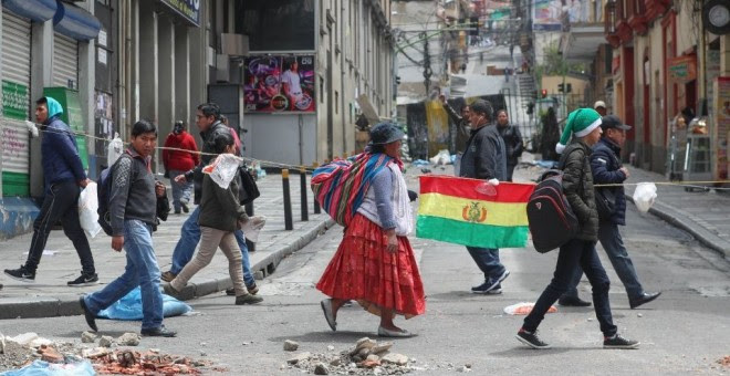 Gente paseando por las calles con una bandera de Bolivia. / EFE