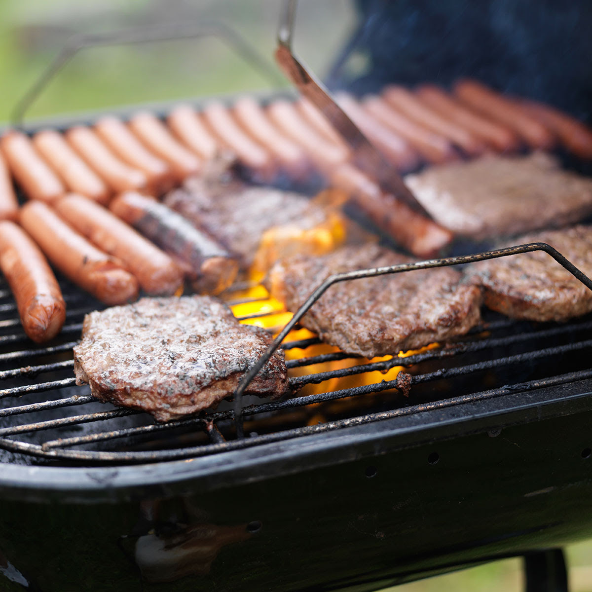 BBQ hot dogs and hamburgers burning on grill